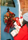 Mujer con regalos envueltos en la puerta principal - foto de stock