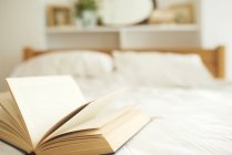 Close up shot of open book on bed — Stock Photo