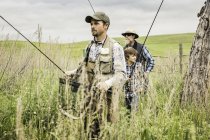 Multi generation family in field carrying fishing rods — Stock Photo