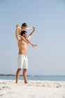 Padre che porta il figlio sulle spalle su una spiaggia — Foto stock