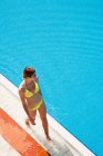 Young woman walking by poolside — Stock Photo