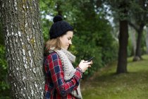 Дівчина-підліток використовує мобільний телефон у лісі — стокове фото