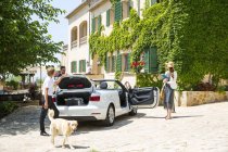 Boutique hotel porter getting luggage for couple arriving in convertible, Majorca, Spain — Stock Photo
