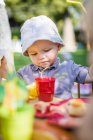 Toddler boy eating at table outdoors — Stock Photo