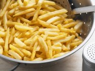 French fries in colander, close up shot — Stock Photo