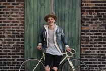 Retrato de jovem encostado à bicicleta, ao ar livre — Fotografia de Stock