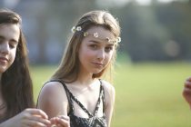 Retrato de menina adolescente vestindo cobertura para a cabeça cadeia margarida no parque — Fotografia de Stock