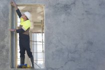 Gestionnaire de site atteignant pour vérifier l'embrasure de porte sur le chantier de construction — Photo de stock