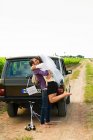 Newlywed couple kissing by vehicle — Stock Photo