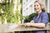 Reife Frau spielt mit Schlauchrohr im Garten — Stockfoto