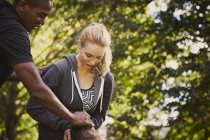 Молодая женщина с личным тренером объясняет подъем ствола дерева в парке — стоковое фото