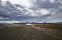 Feldweg in karger Landschaft mit dramatisch bewölktem Himmel — Stockfoto