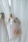 Mädchen blickt durch Vorhang — Stockfoto
