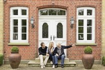 Father and mid adult couple sitting on doorstep — Stock Photo