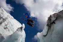 Hiker jumping in between glaciers — Stock Photo