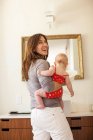 Sonriente madre sosteniendo al bebé - foto de stock