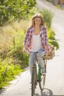 Mulher sorridente ciclismo bicicleta na estrada rural — Fotografia de Stock