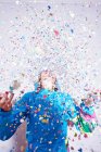 Studio shot of young woman and explosion of confetti — Stock Photo