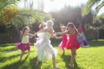 Five energetic girls in fairy costumes playing in garden — Stock Photo