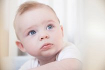 Portrait of blue eyed baby boy staring from crib — Stock Photo