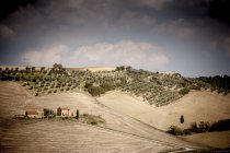 Casas rurales en el campo bajo cielo azul nublado, Toscana, Italia - foto de stock