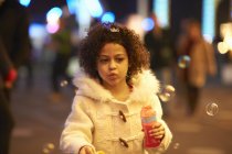 Молода дівчина дме бульбашки, на відкритому повітрі, вночі — стокове фото