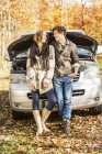 Couple leaning against car that has broken down — Stock Photo