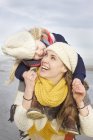 Mulher adulta média carregando filha nos ombros na praia, Bloemendaal aan Zee, Países Baixos — Fotografia de Stock