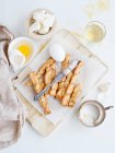 Fresh baked bread sticks and egg on board — Stock Photo