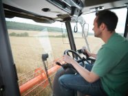 Farmer driving combine harvester — Stock Photo