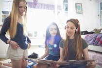 Tres chicas adolescentes mirando la cubierta del disco de vinilo en el dormitorio - foto de stock