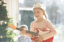 Mädchen spielt an Weihnachten mit Spielzeuggitarre — Stockfoto