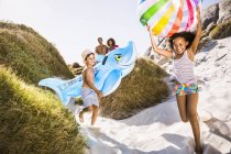 Famille avec deux enfants descendant une dune de sable portant requin gonflable et ballon de plage, Cape Town, Afrique du Sud — Photo de stock