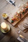 Gravlax salmon salad on wooden board and flaming candle — Stock Photo