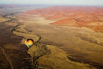 Hot air balloon floating over desert landscape — Stock Photo