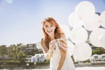 Rothaarige Frau hält Luftballons in die Kamera und lächelt — Stockfoto