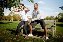 Man guiding woman doing squats in park — Stock Photo