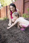 Мать и дочь сеют семена в саду — стоковое фото