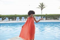 Young woman wearing orange dress at hotel poolside, Rio De Janeiro, Brazil — Stock Photo