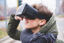 Молодая женщина на улице, в наушниках виртуальной реальности — стоковое фото