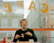 Чоловік в масці для обличчя в кафе — стокове фото
