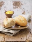 Halbierter weißer Petitpain mit Butter auf Keramikteller und gestreifter Serviette — Stockfoto