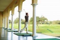 Golfeur dans les arcades pratiquant l'oscillation de golf regardant loin — Photo de stock