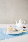 Cupcake and teapot on table — Stock Photo