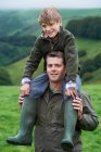 Pai dando filho um porquinho de volta no campo — Fotografia de Stock