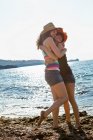 Donne in cappelli da sole che abbracciano sulla spiaggia — Foto stock