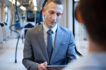 Uomo d'affari che utilizza tablet digitale sul treno — Foto stock
