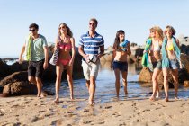 Smiling friends walking on beach, focus on foreground — Stock Photo