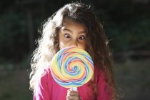 Portrait of girl crossing eyes with lollipop in front of her face in garden — Stock Photo