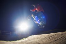 BMX-велосипедист прыгает на велосипеде ночью — стоковое фото